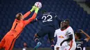 Kiper RB Leipzig, Peter Gulacsi (kiri) meninju bola dari ancaman bek Paris Saint Germain, Abou Diallo, dalam laga lanjutan Liga Champions 2020/21 di Parc des Princes Stadium, Paris, Rabu (25/11/2020). Leipzig kalah 0-1 dari PSG. (AFP/Franck Fife)