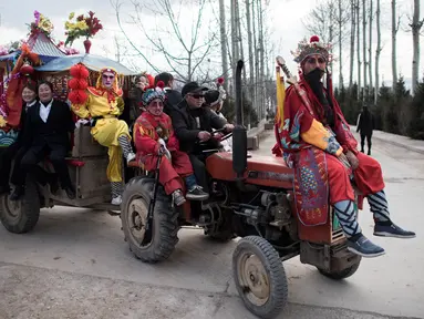 Penduduk desa mengenakan kostum tradisional menumpang traktor jelang festival She Huo di Longxian, provinsi Shaanxi, Tiongkok (27/2). Mereka mengenakan kostum beraneka ragam untuk mengikuti festival She Huo. (AFP Photo/Fred Dufour)