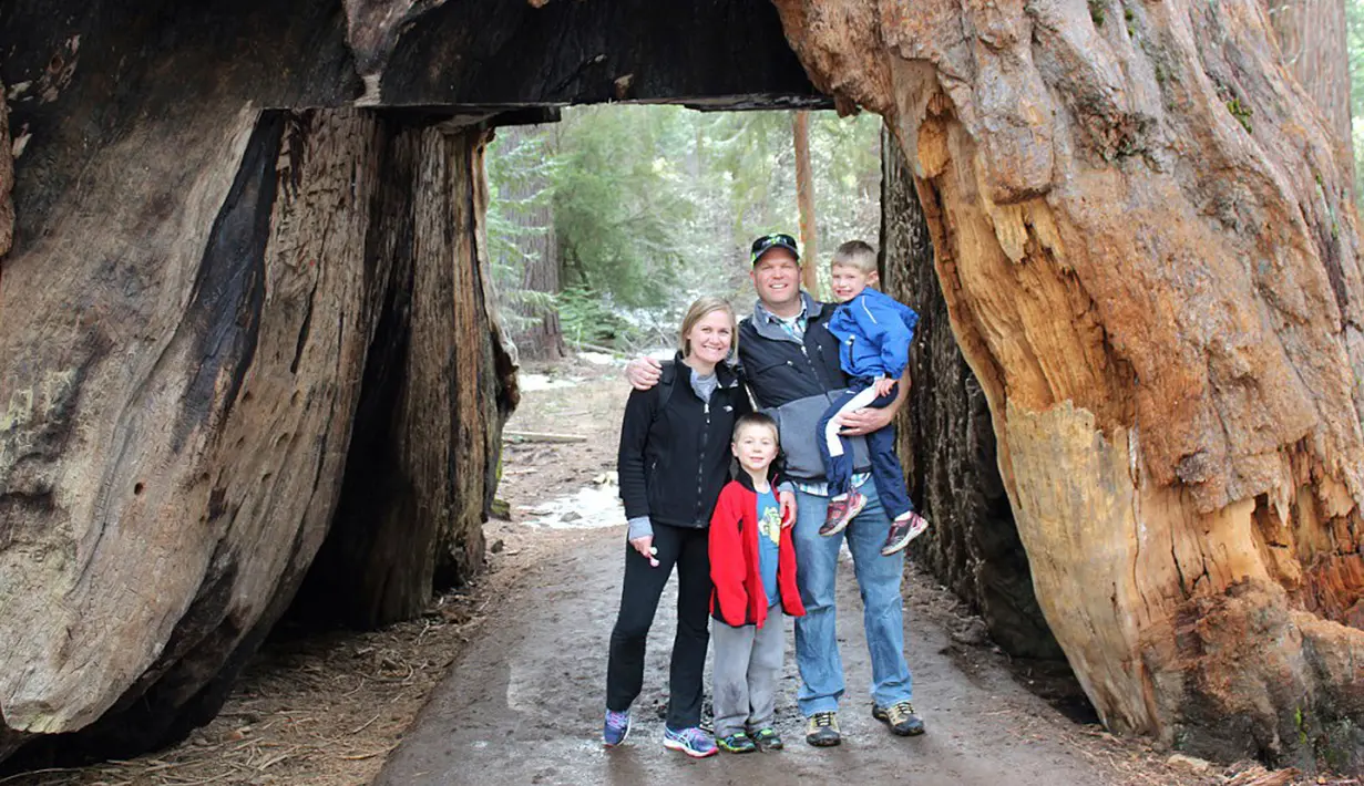 Pengunjung berpose di The Pioneer Cabin Tree, California, AS (Mei 2015). Pohon sequoia raksasa yang jadi ikon di California Sierra Nevada itu roboh pada Minggu (8/1). (AP Photo/ Michael Brown)