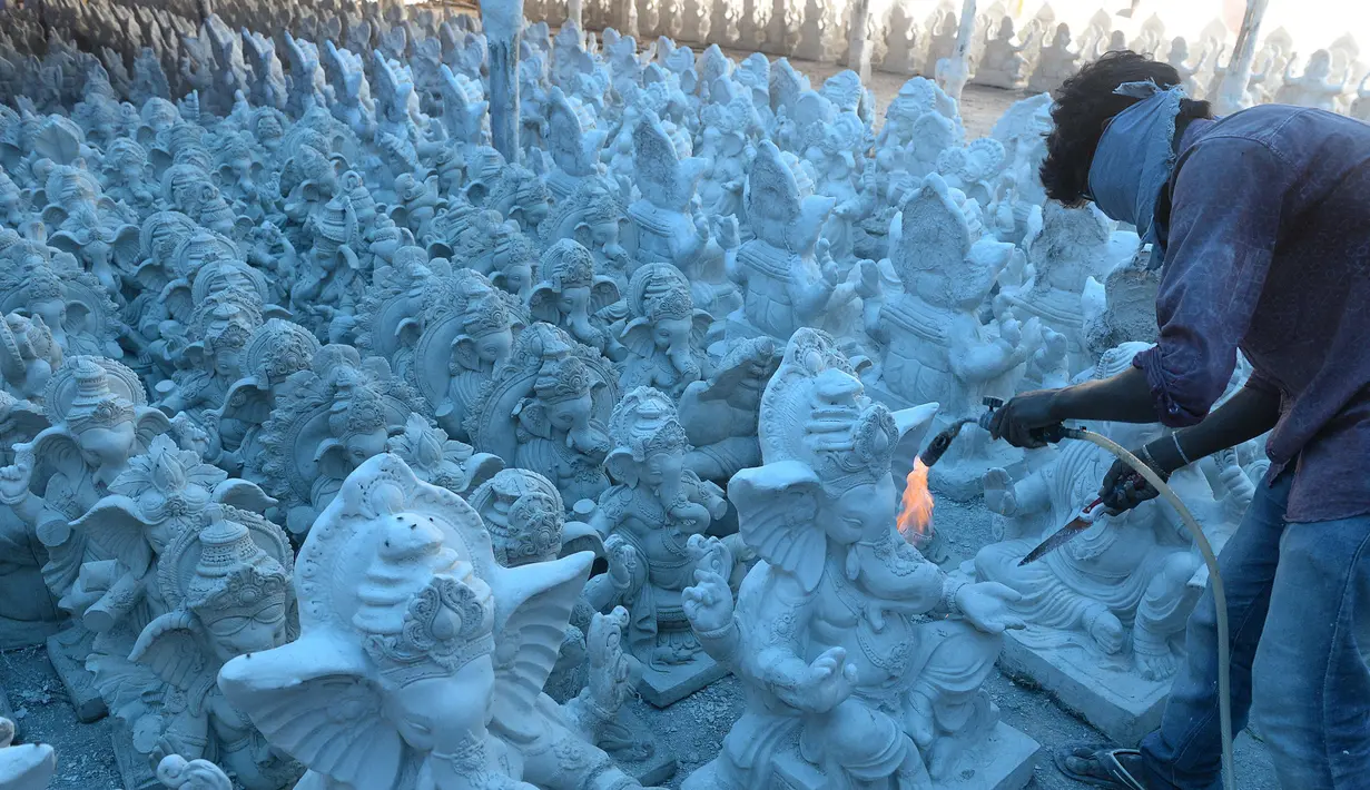 Perajin menyelesaikan pembuatan patung Dewa Ganesha di sebuah bengkel di pinggiran Hyderabad, India, Senin (29/6/2020). Patung Dewa Ganesha banyak ditemukan di berbagai penjuru India termasuk Nepal, Tibet, dan Asia Tenggara. (NOAH SEELAM/AFP)