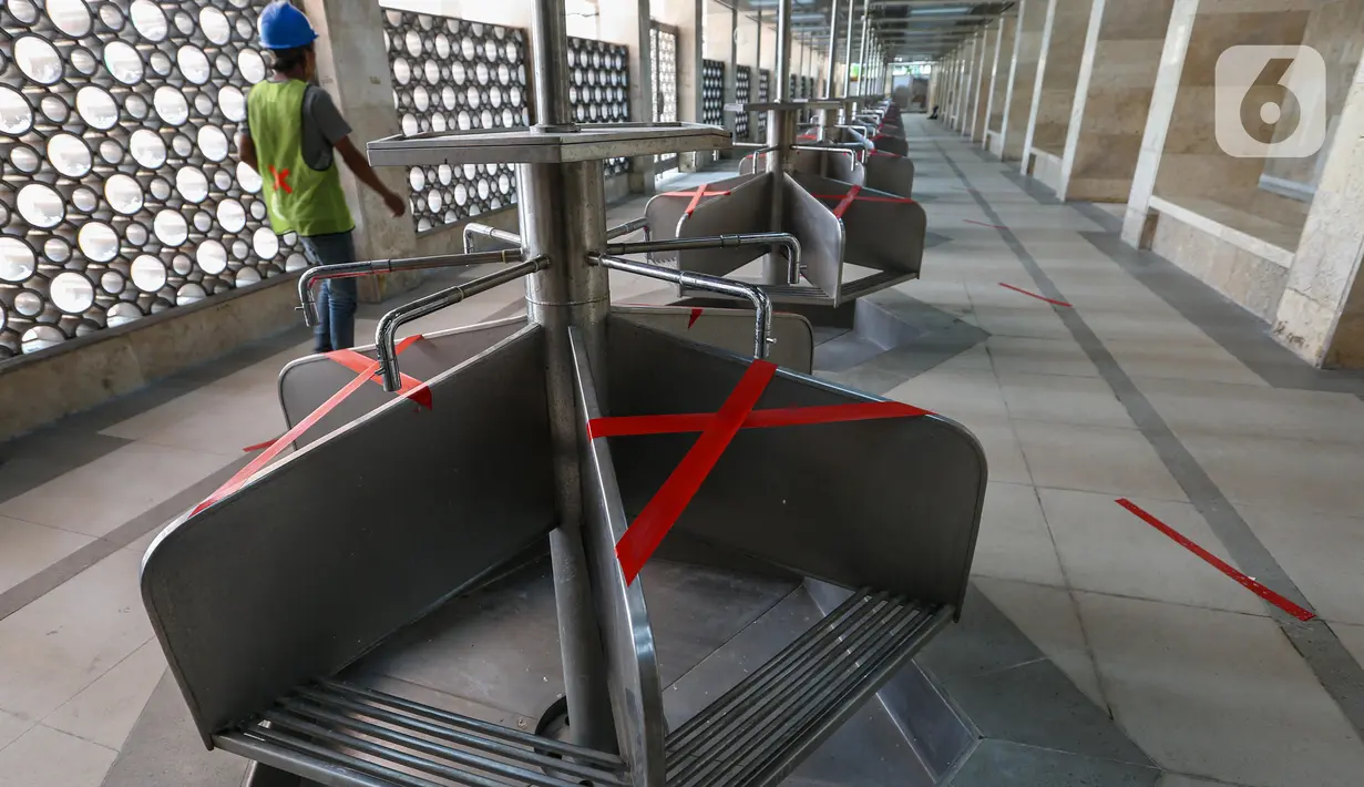 Petugas memasang tanda silang pada bangku di Masjid Istiqlal, Jakarta Pusat,, Selasa (2/6/2020). Masjid Istiqlal merupakan salah satu sarana ibadah yang dipersiapkan menerapkan prosedur standar new normal atau kenormalan baru. (Liputan6.com/Faizal Fanani)