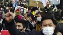 Warga Myanmar yang tinggal di Jepang membawa foto pemimpin Myanmar Aung San Suu Kyi yang kini ditahan saat protes di depan Kementerian Luar Negeri di Tokyo (3/2/2021). Aksi yang terjadi di tengah pandemi ini dijaga ketat oleh polisi Jepang. (AP Photo/Eugene Hoshiko)