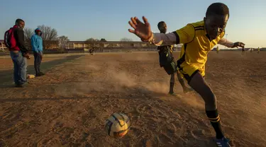 Seorang pemain berusaha mengontrol bola saat bertanding pada laga persahabatan di lapangan yang berdebu di Soweto, Afrika Selatan, Rabu (16/6/2021).  Sejumlah warga bermain bola di lapangan berdebu di Soweto, Afrika Selatan. (AP Photo/Themba Hadebe)