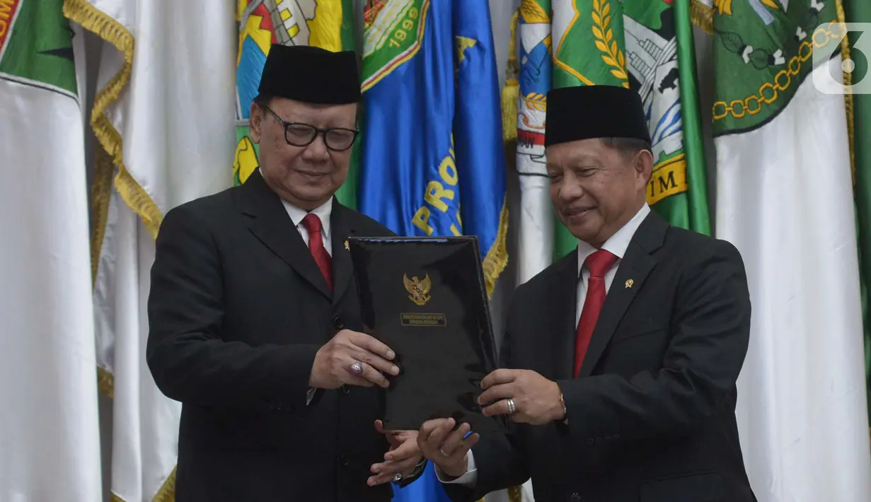 Menteri Dalam Negeri Tito Karnavian (kanan) bersama pejabat lama Tjahjo Kumolo memegang berita acara serah terima jabatan di Kantor Kemendagri, Jakarta, Rabu (23/10/2019). Presiden Jokowi resmi melantik Tito Karnavian menjadi mendagri dalam jajaran Kabinet Indonesia Maju. (merdeka.com/Imam Buhori)