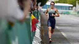 Flora Duffy dari Bermuda berlari di dekat beberapa penonton di sepanjang jalan selama kompetisi triathlon nomor individu putri Olimpiade Tokyo 2020 di Odaiba Marine Park, Selasa (27/7/2021). Flora Duffy menjadi penyumbang medali emas untuk negara berpenduduk 60 ribu orang itu. (AP/Eugene Hoshiko)