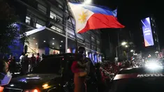 Seorang pendukung mengibarkan bendera saat mereka tiba di markas besar Ferdinand "Bongbong" Marcos Jr di Mandaluyong, Filipina pada Senin malam (9/5/2022). Ferdinand Marcos Jr., putra mendiang Ferdinand Marcos, diktator Filipina yang terguling, jauh memimpin dalam penghitungan suara tidak resmi pemilu presiden hari Senin. (AP Photo/Aaron Favila)