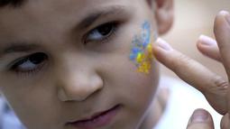 Seorang anak laki-laki didandani dengan warna nasional Ukraina untuk perayaan hari Kemerdekaan Ukraina di Chichester, Inggris selatan, Sabtu, 27 Agustus 2022. Chichester dinobatkan sebagai daerah paling dermawan di negara itu untuk menampung pengungsi Ukraina. (AP Photo/Frank Augstein)