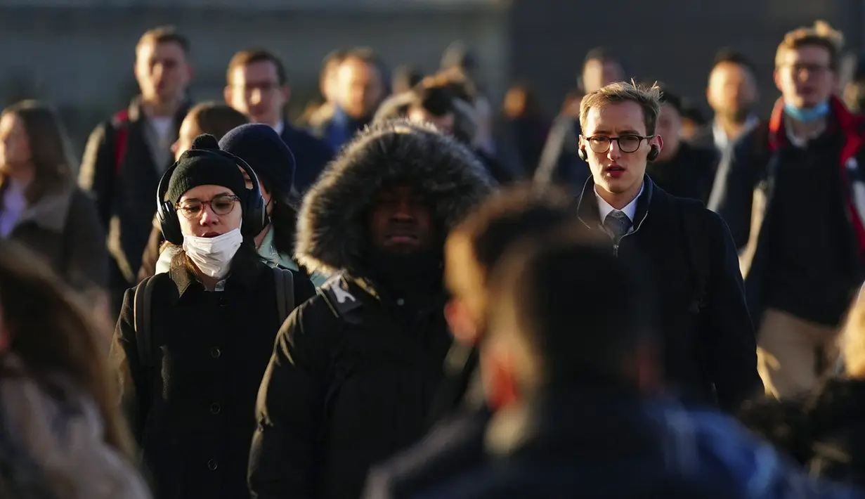Komuter melintasi London Bridge untuk bekerja menuju kantor di London, Kamis (20/1/2022). Pemerintah Inggris mengakhiri pembatasan COVID-19, termasuk mandat masker, bekerja dari rumah dan paspor vaksin mulai Kamis. (AP Photo/Kirsty Wigglesworth)