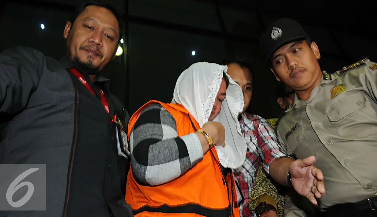 Sri Hartini dikawal petugas polisi meninggalkan gedui KPK usai menjalani pemeriksaan, Jakarta, Sabtu (31/12). KPK menetapkan Bupati Klaten Sri Hartini dan Suramlan terkait dugaan kasus suap pengaturan jabatan. (Liputan6.com/Helmi Afandi)