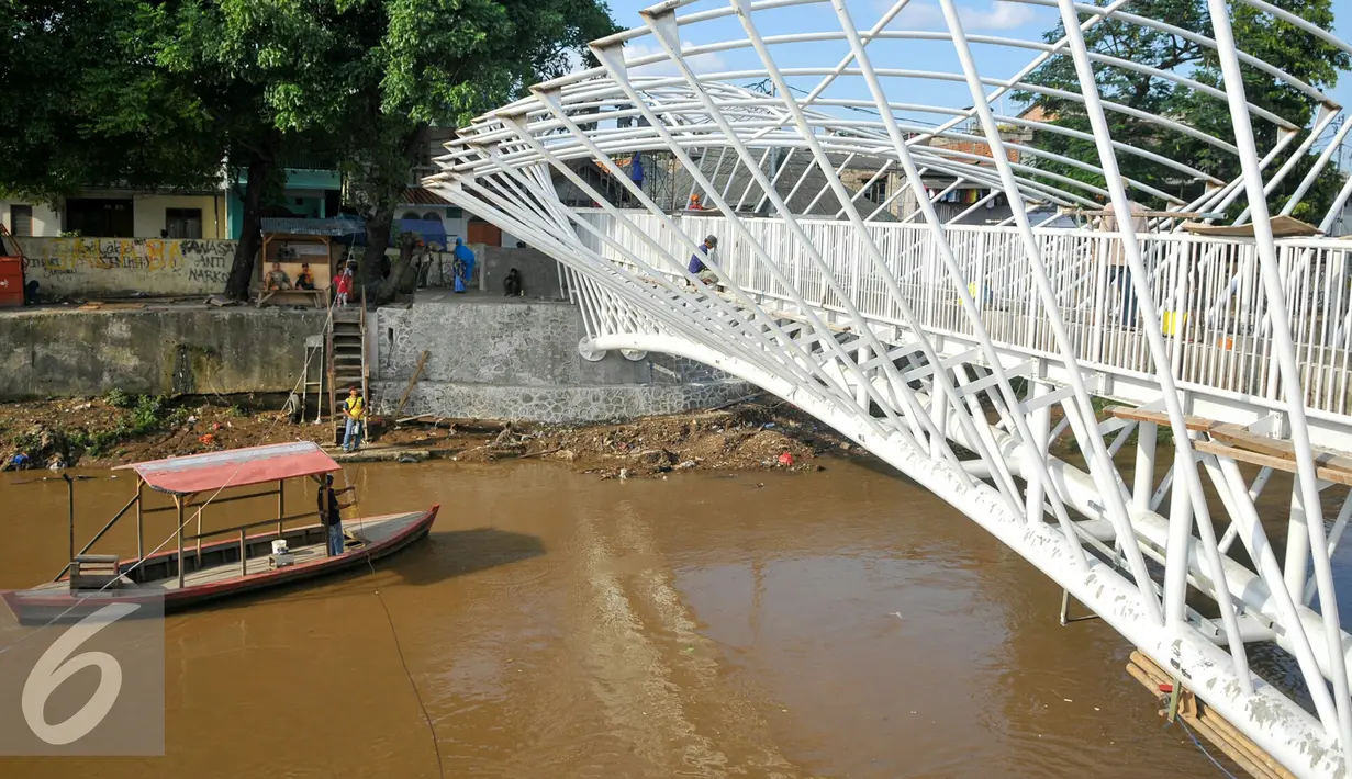 Perahu melintas di bawah Pembangunan jembatan penyeberangan orang (JPO) sungai Ciliwung, Jakarta, Senin (4/4). Rencaanya JPO tersebut siap digunakan pada 6 April mendatang. (Liputan6.com/Yoppy Renato)
