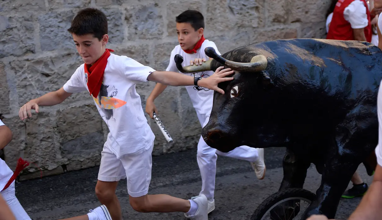 Anak-anak berlarian saat mengikuti Encierro Txiki selama Festival San Fermin di Pamplona, Spanyol (13/7). Small Bull Run hanya dimainkan anak-anak, dan berbeda dengan pria dewasa yang menggunakan banteng sungguhan saat Festival. (AFP Photo/Ander Gillenea)