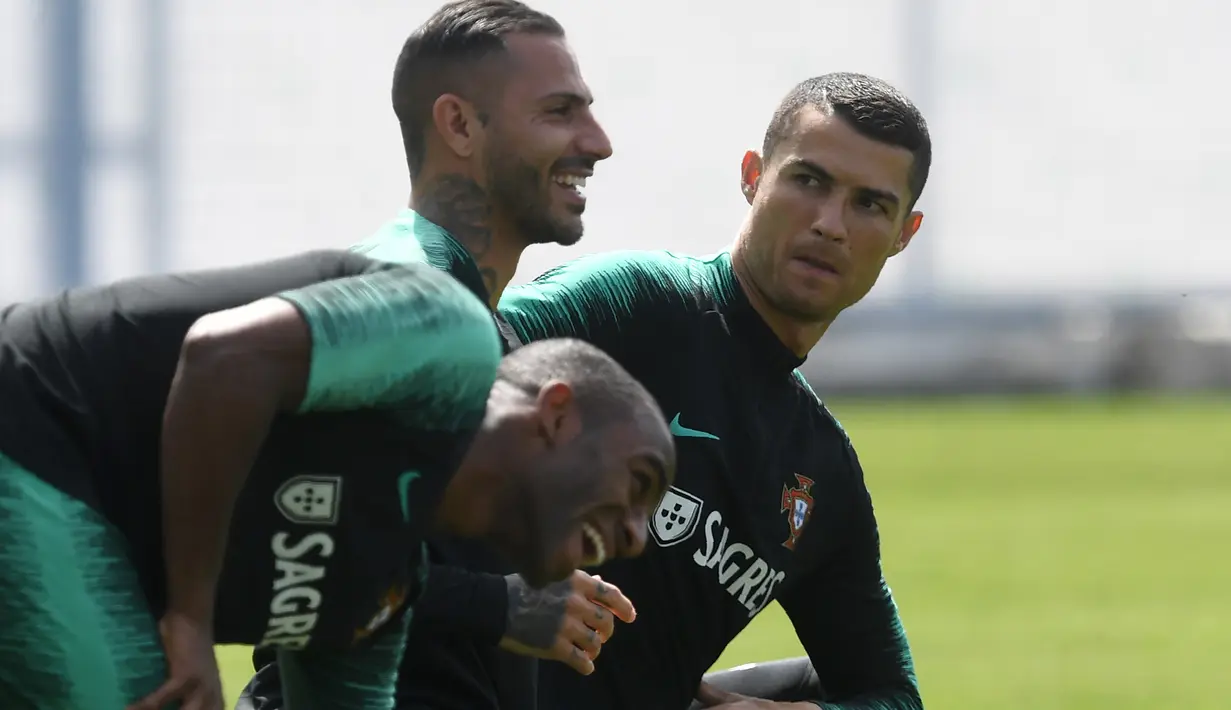 Ekspresi Cristiano Ronaldo (kanan) saat pemanasan dengan Ricardo Quaresma dan Ricardo Pereira (kiri) pada sesi latihan di Kratovo, Moskow, (12/6/2018). Portugal akan mejalani laga perdana grup B melawan Spanyol. (AFP/Francisco Leong)