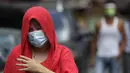 Seorang wanita mengenakan masker berjalan di luar desa yang dikunci di Manila, Filipina (11/3/2021). Kota-kota lain di ibu kota memberlakukan kembali penguncian di beberapa lingkungan dan jam malam yang lebih panjang setelah mendeteksi infeksi baru. (AP Photo/Aaron Favila)