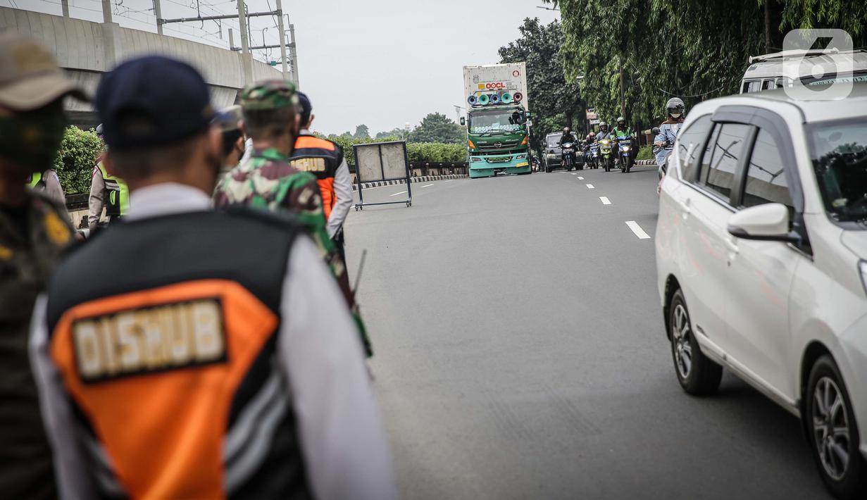 Petugas mengawasi kendaraan yang melintasi pos cekpoin penyekataan arus mudik di kawasan Pasar Jumat, Kamis (6/5/2021). Penyekatan dan cek poin dilakukan saat penerapan larangan mudik Lebaran 2021 sebagai upaya pencegahan penularan COVID-19. (Liputan6.com/Faizal Fanani)