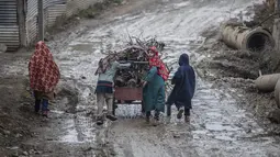 Anak-anak Kashmir mendorong gerobak berisi kayu bakar pada hari yang dingin di pinggiran Srinagar, Kashmir yang dikuasai India, Senin (27/12/2021). (AP Photo/Mukhtar Khan)
