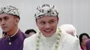 <p>Senyum semringah Rizky Febian saat diantar ke meja akad nikah. Dia mengenakan busana pengantin adat Sunda berwarna serba putih. (Foto: Instagram/ axioo)</p>