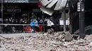Warga berkumpul di dekat sebuah bangunan yang rusak setelah gempa magnitudo 5,8 di pusat perbelanjaan populer Chapel Street di Melbourne, Rabu (22/9/2021). Dilaporkan, warga Melbourne yang panik berlarian ke jalanan setelah guncangan gempa terasa di gedung-gedung. (William WEST/AFP)