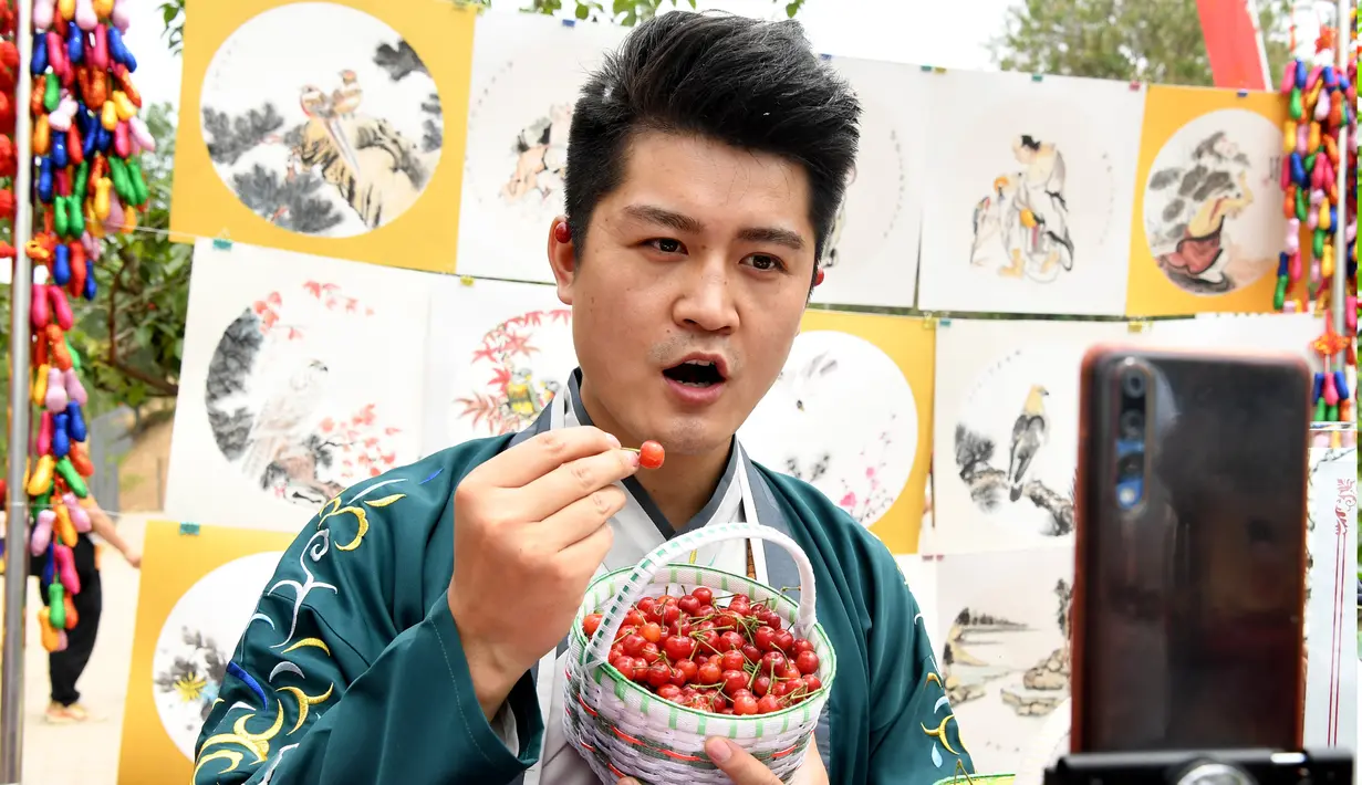 Seorang warga lokal memperkenalkan ceri melalui siaran langsung (livestreaming) via telepon seluler dalam festival ceri yang digelar di kawasan wisata Cherry Vale di Distrik Erqi, Zhengzhou, Provinsi Henan, China tengah, (6/5/2020). (Xinhua/Hao Yuan)