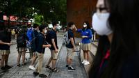 Siswa dengan mengenakan masker antre untuk memeriksa suhu mereka di sekolah Marie Curie di Hanoi, Senin (4/5/2020). Vietnam membuka kembali aktivitas sekolah yang ditutup selama tiga bulan setelah dilaporkan tidak ada kasus virus corona COVID-19 baru hingga Sabtu, 2 Mei 2020. (Manan VATSYAYANA/AFP)