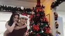 Ranty Maria dan Rayn Wijaya tampil romantis di depan pohon Natal. Kenakan busana kasual bertema Natal, Rayn Wijaya kenakan topi santa yang unik dan Ranty Maria kenakan bando bertanduk rusa [@rantymaria]
