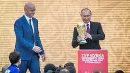Presiden Rusia Vladimir Putin dan Presiden FIFA, Gianni Infantino bersiap menaruh trofi Piala Dunia dalam pembukaan upacara  "FIFA World Cup Trophy Tour" di stadion Luzhniki di Moskow (9/9). (AFP Photo/Mladen Antonov) 