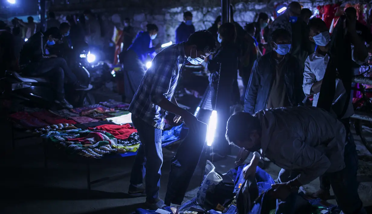 Warga Nepal yang mengenakan masker sebagai tindakan pencegahan terhadap virus corona COVID-19 berada di kios pedagang pinggir jalan, Kathmandu, Nepal, Selasa (13/10/2020). (AP Photo/Niranjan Shrestha)