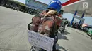 Pemudik sepeda motor menempelkan pesan di tasnya saat  mengisi bahan bakar di SPBU kawasan Brebes, Jawa Tengah, Minggu (2/6/2019). Sejumlah SPBU di Brebes terpantau ramai oleh para pemudik yang mengisi bahan bakar kendaraannya. (Liputan6.com/Herman Zakharia)