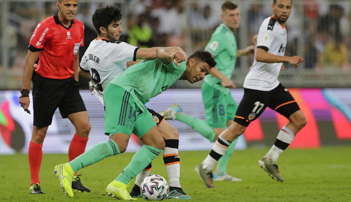 Gelandang Real Madrid, Casemiro, berebut bola dengan pemain Valencia, Carlos Soler, pada laga Piala Super Spanyol di Stadion King Abdullah Sport City, Arab Saudi, Rabu (8/1/2020). Real Madrid menang 3-1 atas Valencia. (AP/Amr Nabil)