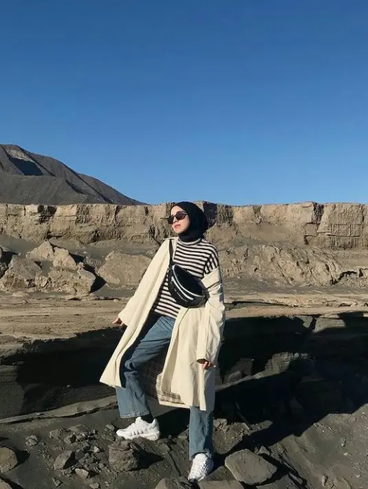 Gaya kasual bisa kamu dapatkan dengan padu padan celana jeans, stripes turtleneck, dan raincoat. Tak lupa, tambahkan waist bag untuk menciptakan tampilan stylish di musim dingin. (FOTO: Instagram.com/ameliaelle).