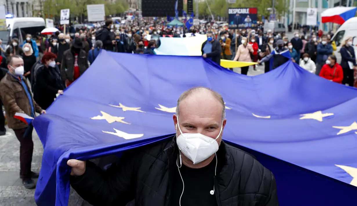 Pria memegang bendera Uni Eropa saat demonstrasi, Praha, Republik Ceko, Kamis (29/4/2021). Ribuan warga berunjuk rasa menentang Presiden Milos Zeman dan menuduhnya melakukan pengkhianatan atas sikap pro Rusia pada dugaan partisipasi mata-mata Rusia dalam ledakan di Ceko. (AP Photo/Petr David Josek)