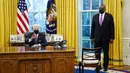 Menteri Pertahanan Lloyd Austin mendengarkan Presiden AS Joe Biden berbicara sebelum menandatangani Perintah Eksekutif yang membatalkan larangan bagi transgender untuk masuk militer AS pada era Donald Trump di Kantor Oval Gedung Putih, Washington, Senin (25/1/2021). (AP Photo/Evan Vucci)