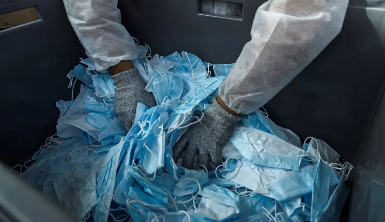 Pekerja menyiapkan masker bekas untuk didaur ulang di perusahaan Plaxtil, Chatellerault, Prancis, 25 Agustus 2020. Startup di Prancis, Plaxtil, mendaur ulang masker dan plastik untuk dijadikan pelindung wajah, pembuka pintu, dan pengencang masker. (GUILLAUME SOUVANT/AFP)