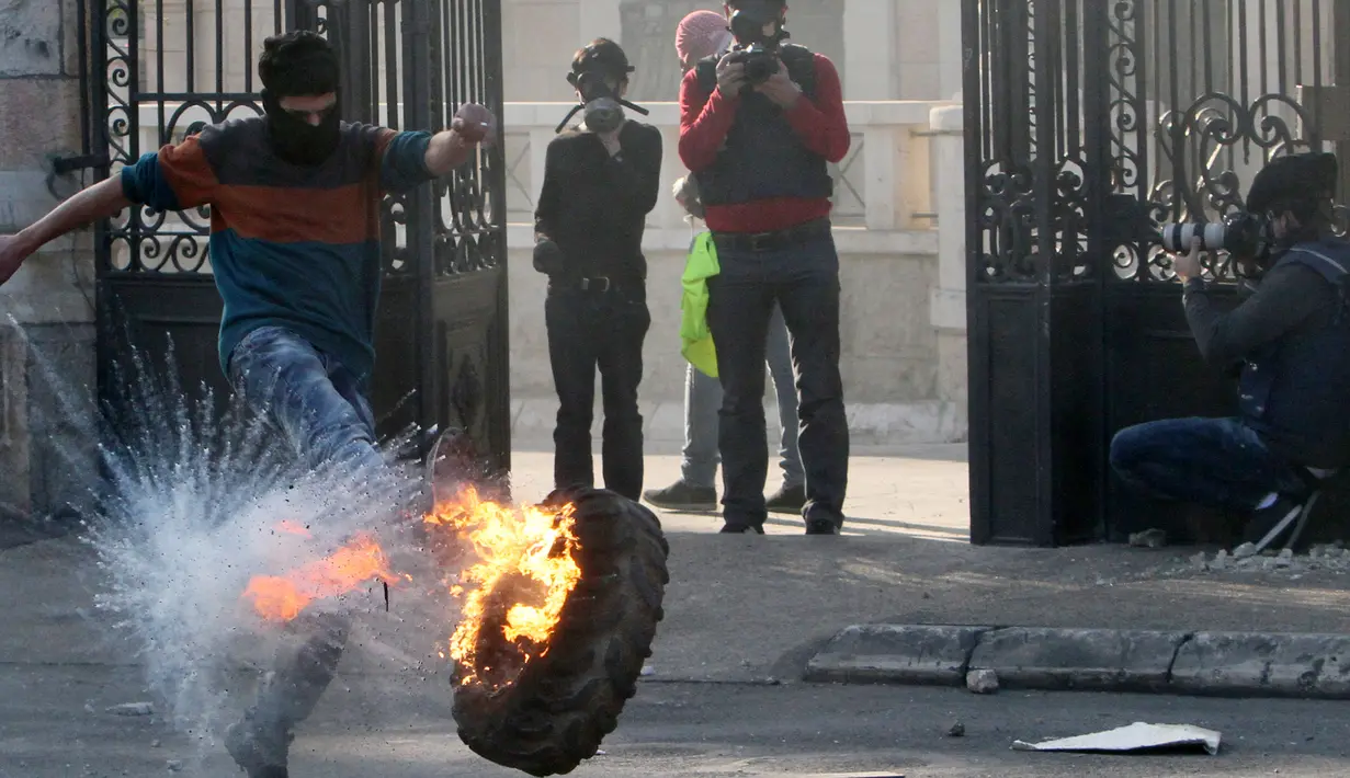 Pengunjuk rasa Palestina menendang ban terbakar dalam saat bentrokan dengan pasukan keamanan Israel di pintu masuk utama kota Bethlehem, Yerusalem (25/12/2015). (AFP Photo/Musa Al-Shaer)