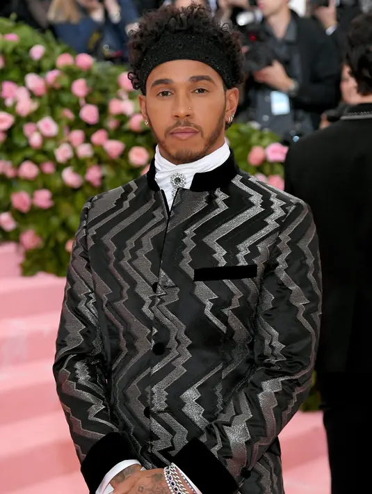 Pembalap Mercedes, Lewis Hamilton saat menghadiri Met Gala 2019 di Metropolitan Museum of Art di New York, AS (6/5/2019). Pria 34 asal Inggris ini tampil dengan jas hitam memamerkan desain zig-zag perak dan celana yang senada. (AFP Photo/Neilson Barnard)