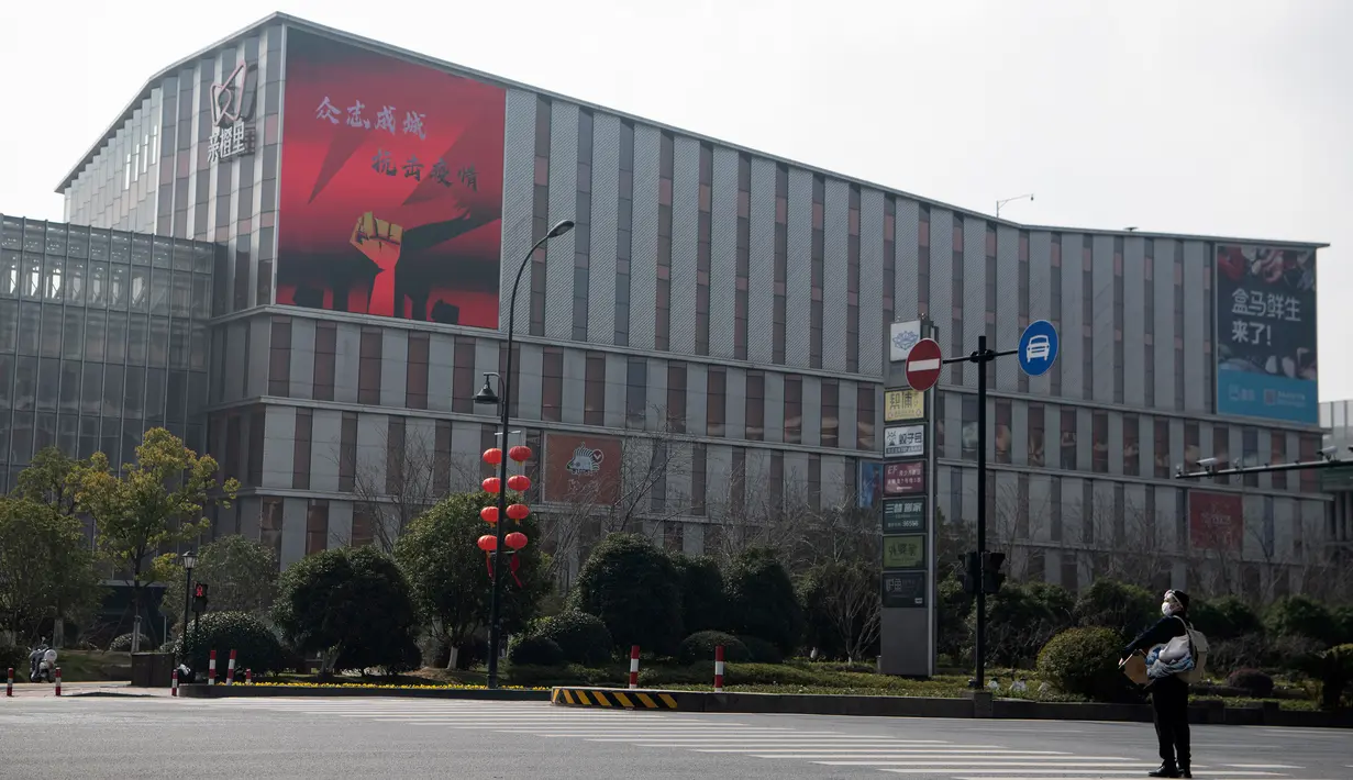 Pria bermasker berdiri dekat supermarket Alibaba di Kota Hangzhou, Provinsi Zhejiang, China, Rabu (5/2/2020). Pemerintah Hangzhou memberlakukan pembatasan pergerakan bagi warganya menyusul mewabahnya virus corona. (NOEL CELIS/AFP)