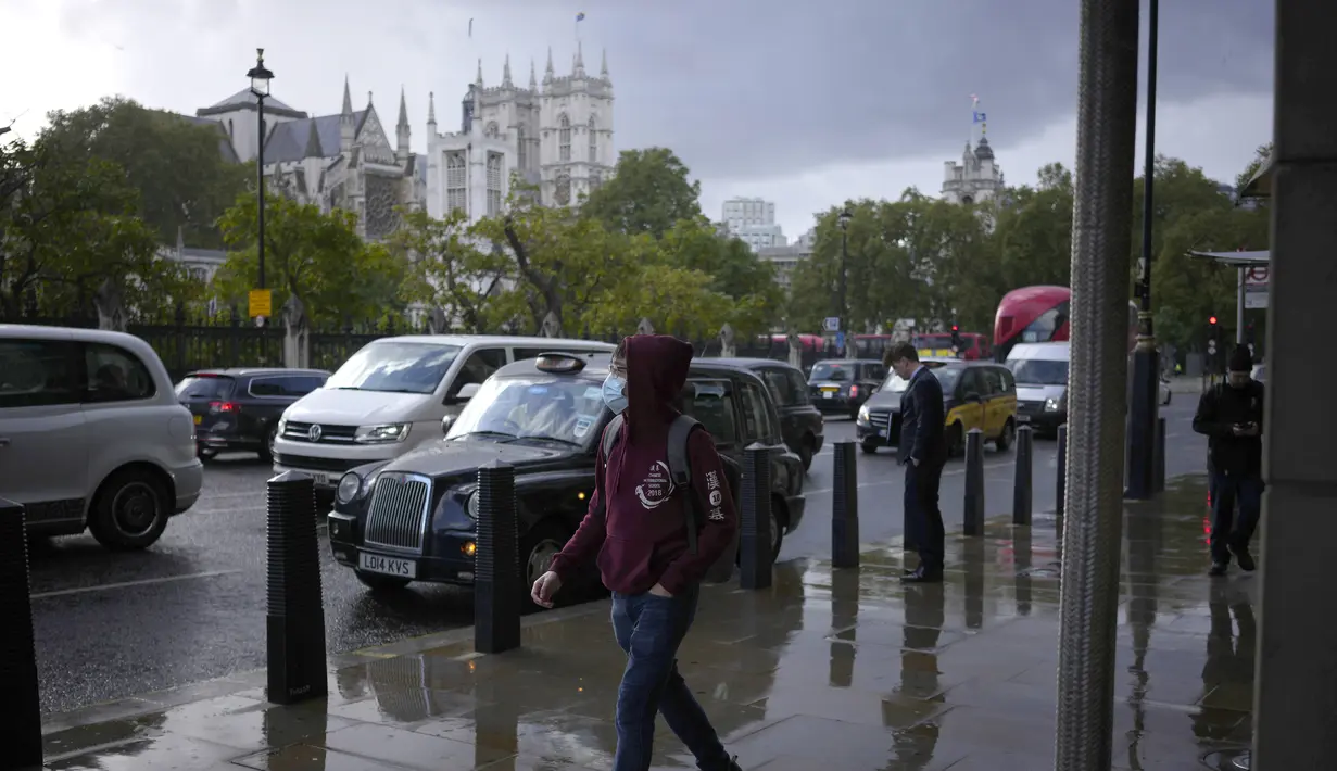 Seorang pria yang mengenakan masker berjalan dengan latar belakang Westminster Abbey dari kejauhan, di London, Rabu (20/10/2021). Eropa menjadi satu-satunya wilayah di dunia dengan kenaikan kasus COVID-19 di mana Inggris, Rusia dan Turki menyumbang kasus terbanyak di Eropa. (AP Photo/Matt Dunham)