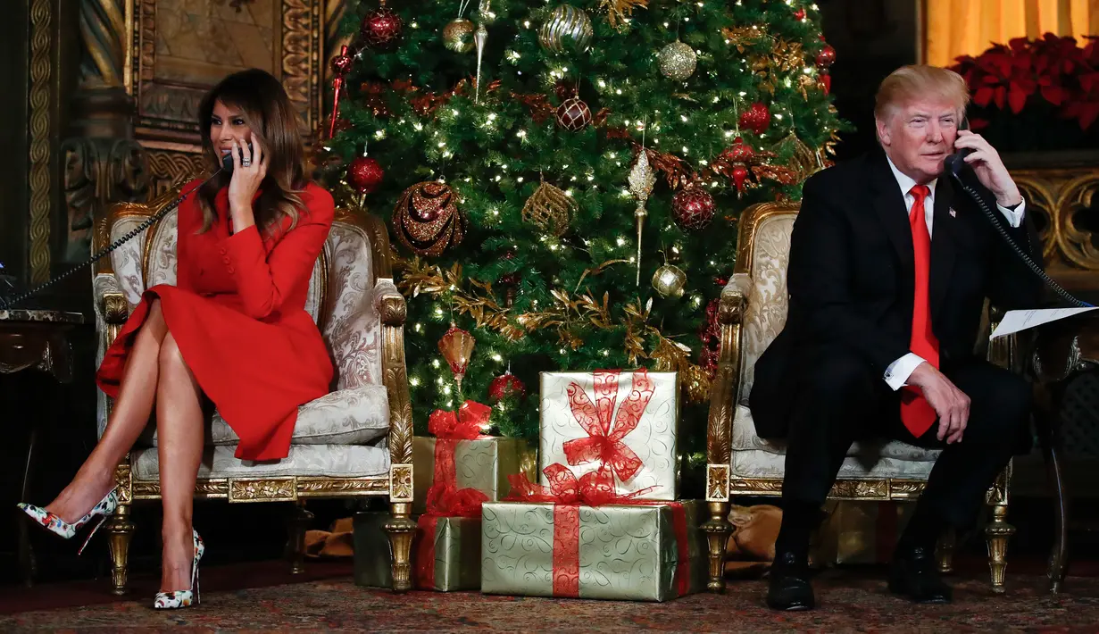 Presiden AS Donald Trump dan istrinya, Melania Trump berbicara di telepon dengan anak-anak saat mereka mengikuti NORAD Tracks Santa di Palm Beach, AS (24/12). NORAD Tracks Santa adalah acara Natal melacak posisi Sinterklas. (AP Photo/Carolyn Kaster)