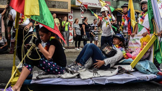 Warga Kolombia turun ke jalanan dan bermalas-malasan di atas tempat tidur pada pawai merayakan Hari Kemalasan Sedunia di Itagui, dekat Medellin, Minggu (19/8). Perayaan ini membantu mengingatkan mereka akan perlunya memanjakan diri (AFP/JOAQUIN SARMIENTO)