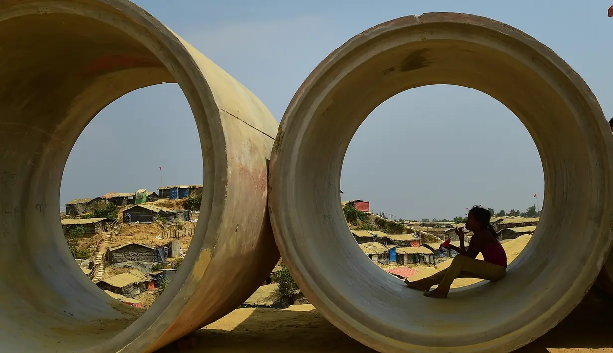 Seorang bocah pengungsi Rohingya duduk di dalam pipa limbah di kamp pengungsi Kutupalong, Bangladesh (5/4). Pemerintah Bangladesh mengatakan akan memulai relokasi sekitar 100.000 pengungsi Rohingya. (AFP Photo/Munir Uz Zaman)