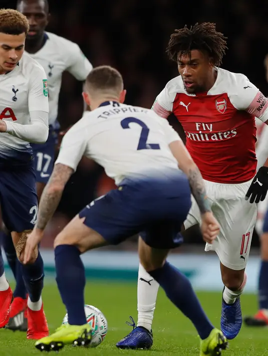 Pemain Arsenal, Alex Iwobi berusaha melewati pemain Tottenham Hotspur, Kieran Trippier pada perempat final Piala Liga Inggris di Stadion Emirates, Kamis (20/12). Tottenham melaju ke babak semifinal seusai menaklukkan Arsenal 2-0. (AP/Frank Augstein)