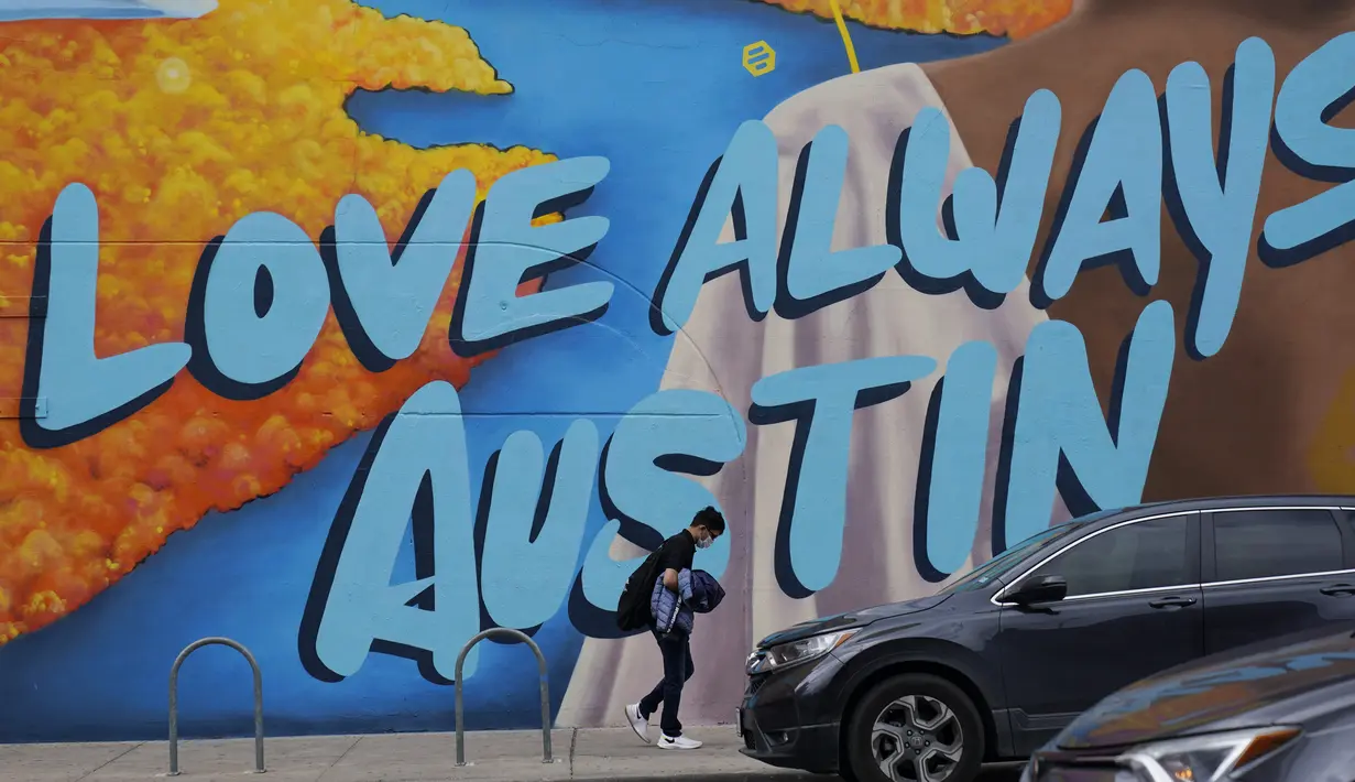 Seorang pejalan kaki yang mengenakan masker untuk meminimalisir penyebaran Covid-19 berjalan melintasi pusat kota Austin, Texas, Selasa (9/3/2021). Mandat Gubernur Texas Greg Abbott yang mencabut keharusan mengenakan masker di negara bagiannya akan berlaku penuh mulai 10 Maret.. (AP Photo/Eric Gay)
