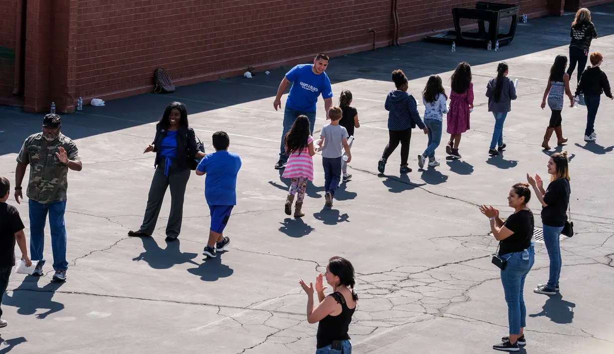 Para staf menyambut siswa setibanya di tempat evakuasi setelah insiden penembakan di SD North Park, San Bernardino di California, Senin (10/4). Dua siswa yang tertembak dalam kondisi kritis dan diterbangkan ke rumah sakit. (AP Photo/Ringo H.W. Chiu)