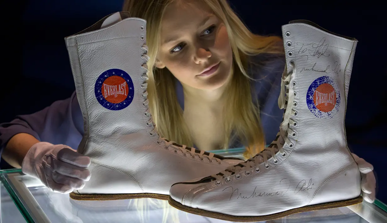 Pegawai menata sepatu boot yang dipakai dan ditandatangani oleh Muhammad Ali saat kejuaraan tinju melawan Jimmy Young pada 1975, dalam sesi pemotretan pameran tentang Ali bertajuk "I Am The Greatest", di O2 Arena, London, Kamis (3/3). (JUSTIN TALLIS/AFP)