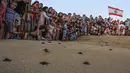 Sejumlah pengunjung melihat pelepasan tukik di pantai al-Mansouri dekat kota Tyre, Lebanon selatan (31/7/2019). Pelepasan ratusan anak penyu ini bagian pelestarian hewan yang terancam punah. (AFP Photo/Mahmoud Zayyat)