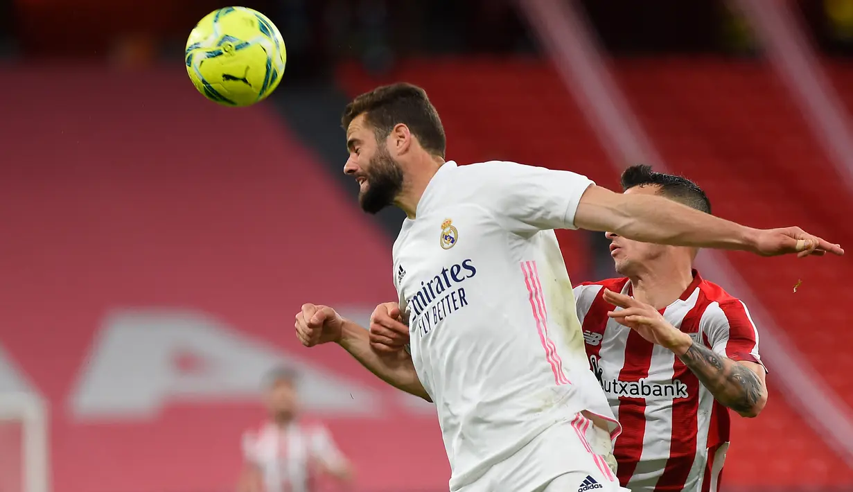 Bek Real Madrid, Nacho Fernandez (kiri) bersaing dengan pemain depan Athletic Bilbao, Alex Berenguer pada pekan ke-37 La Liga di San Mames, Minggu (15/5/2021). Real Madrid berhasil menang di laga sulit yang berlangsung di markas Bilbao dengan skor tipis 1-0. (Ander GILLENEA / AFP)