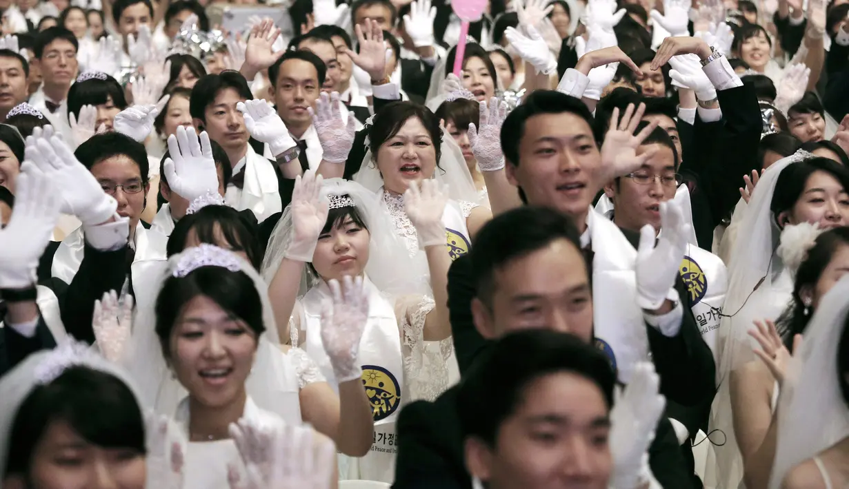 Pasangan pengantin mengangkat tangan mereka saat menghadiri upacara pernikahan massal di Cheong Shim Peace World Center, Gapyeong, Korea Selatan, Senin (27/8). (AP Photo/Ahn Young-joon)