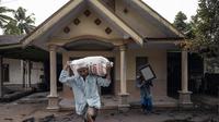 Seorang warga menyelamatkan barang-barangnya di area yang tertutup abu vulkanik setelah letusan gunung Semeru di desa Sumber Wuluh di Lumajang, Jawa Timur, Minggu (5/12/2021). (AFP /Juni Kriswanto)