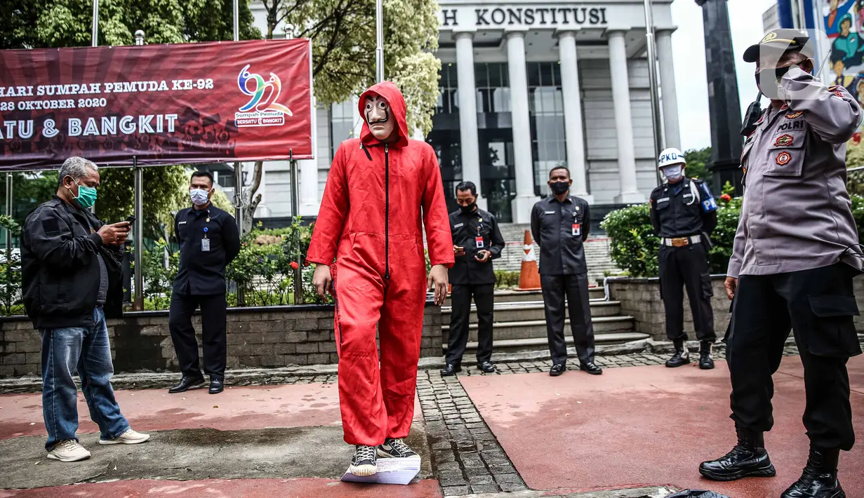 Seorang mahasiswa dari Mahasiswa Independen secara simbolis menginjak salinan naskah UU Cipta Kerja di depan Gedung MK, Jakarta, Selasa (27/10/2020). Mahasiswa menyatakan aksi tersebut bentuk ketidakpercayaan kepada MK bila proses uji materi UU Cipta Kerja dilakukan. (Liputan6.com/Faizal Fanani)