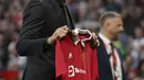 Pemain baru Manchester United Casemiro memegang jerseynya sebelum sesaat sebelum laga MU vs Liverpool dimulai di stadion Old Trafford, di Manchester, Inggris, Senin (22/8/2022). Casemiro yang berpakaian serba hitam, mulai dari jas sampai kemeja yang dikenakannya, berjalan menuju tengah lapangan. (AP Photo/Dave Thompson)