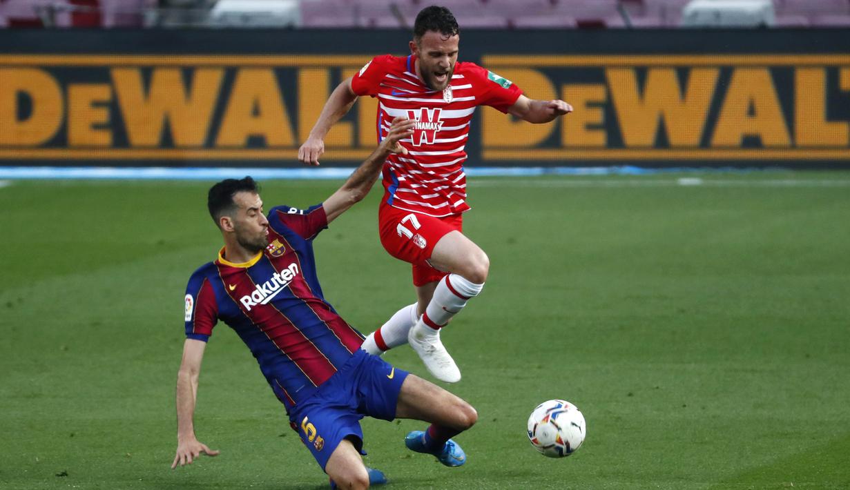 Gelandang Barcelona, Sergio Busquets, berebut bola dengan pemain Granada, Quini, pada laga Liga Spanyol di Stadion Camp Nou, Jumat (30/4/2021). Barcelona takluk dengan skor 1-2. (AP/Joan Monfort)